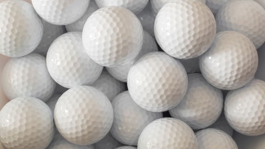 A close-up image of numerous white golf balls grouped together, showing their dimpled textures.